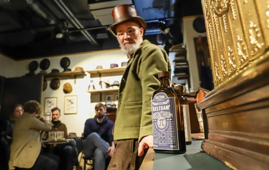 On the Trail of the Green Fairy - Absinthe tasting in Cologne Man with top hat next to absinthe bottle in historical room during tasting.