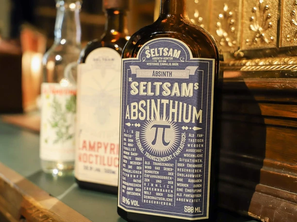 Absinth-Tasting in Köln Nahaufnahme mehrerer Absinthflaschen auf einer Theke in warmem Licht