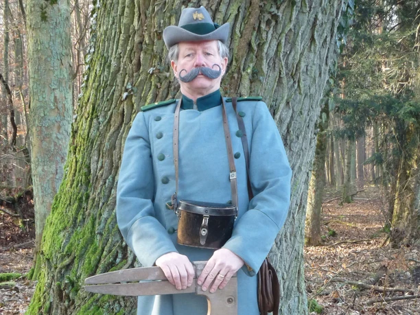 Schäfer Christian in historischer Uniform Mann in historischer Uniform mit Säge im Wald