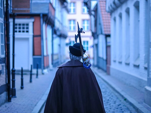 Mit dem Nachtwächter durch die Celler Altstadt Nachtwächter in historischer Tracht mit Hellebarde in einer Gasse der Celler Altstadt.