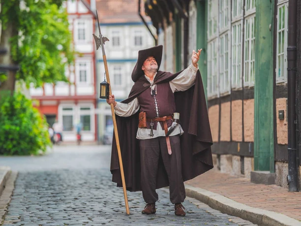Mit dem Nachtwächter durch die Celler Altstadt Nachtwächter in historischer Tracht mit Hellebarde und Laterne in einer Gasse der Celler Altstadt.