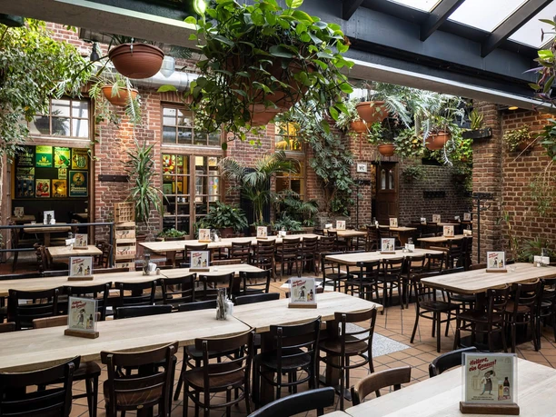 HELLERS Brewery A large courtyard with wooden tables, brick walls, and lots of hanging plants.