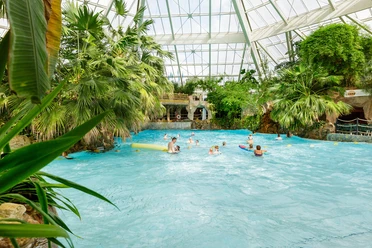 Center-parcs-aqua-mundo-bispingen.jpg Badegäste im Wellenbecken des Aqua Mundo Bispinger Heide, umgeben von tropischen Pflanzen.