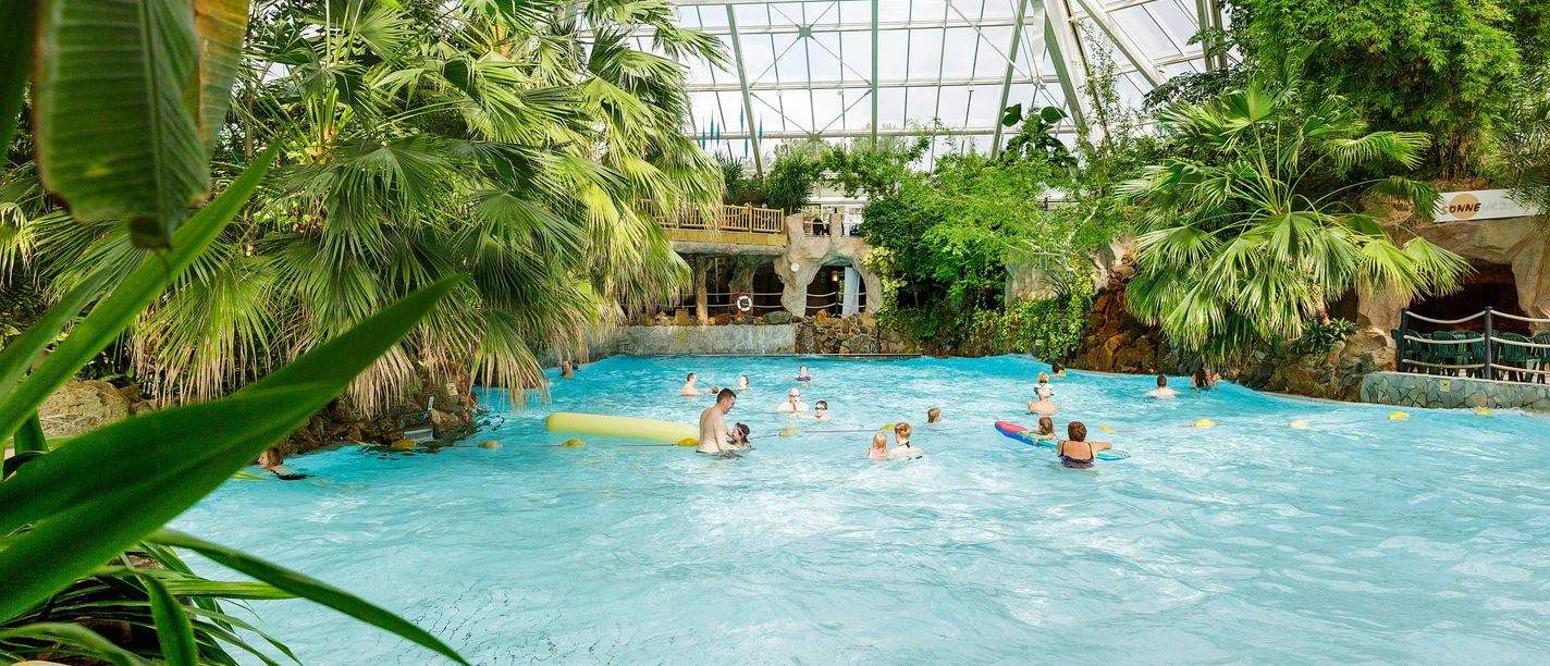 Center-parcs-aqua-mundo-bispingen.jpg Badegäste im Wellenbecken des Aqua Mundo Bispinger Heide, umgeben von tropischen Pflanzen.