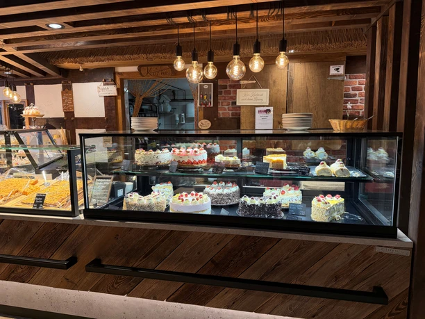 Vielfältige Torten und Kuchen in einer rustikalen Theke mit Glasvitrinen und Holzverkleidung.