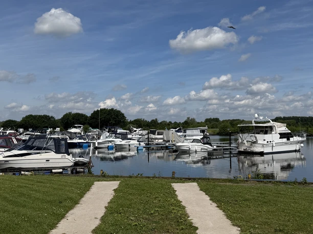 Blick von einer Rasenfläche auf die in der Marina Mehlbergen an Stegen liegenden Motorboote.