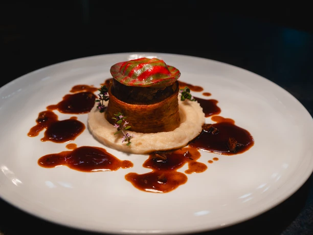 Gerichte im Hieronymus Kunstvoll angerichtetes Gericht mit Püree, Gemüse und dunkler Sauce auf weißem Teller