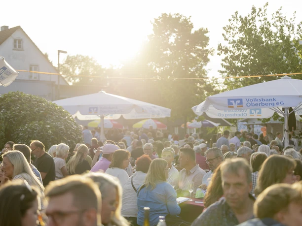 Waldbröler Weinfest Große Menschenmenge bei einem sommerlichen Fest unter Sonnenschirmen im warmen Gegenlicht