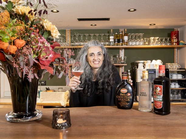 Restaurant Löwen Willisau Gastgeberin im Restaurant Löwen Willisau an der Bar mit Glas und Auswahl an Spirituosen im Hintergrund