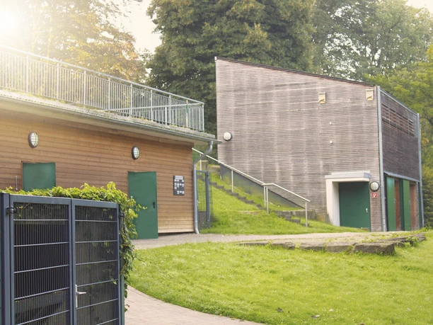 Holzverkleidete Gebäude der Lehrwerkstatt im Herminghauspark Velbert, umgeben von Parkgrün.