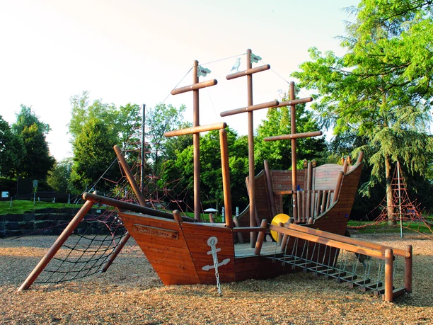 Das Piratenbot auf dem Spielplatz im Herminghauspark in Velbert Hölzernes Piratenschiff als Spielplatzgerät mit Masten und Kletternetzen im Herminghauspark in Velbert.
