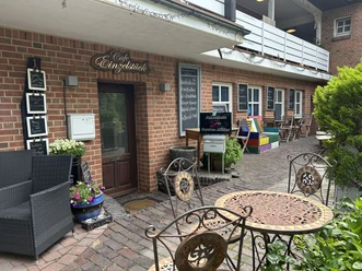 Café Einzelstück Außenansicht des Café Einzelstück mit Sitzplätzen auf der Terrasse vor dem Backsteingebäude.