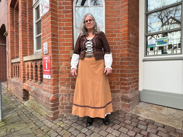 Marktfrau Susanna Gästeführerin Marktfrau Susanna in historischer Tracht vor einem Backsteingebäude in Nienburg.