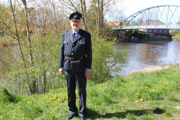 A tour guide in historical uniform is standing on the banks of the Weser in Nienburg.