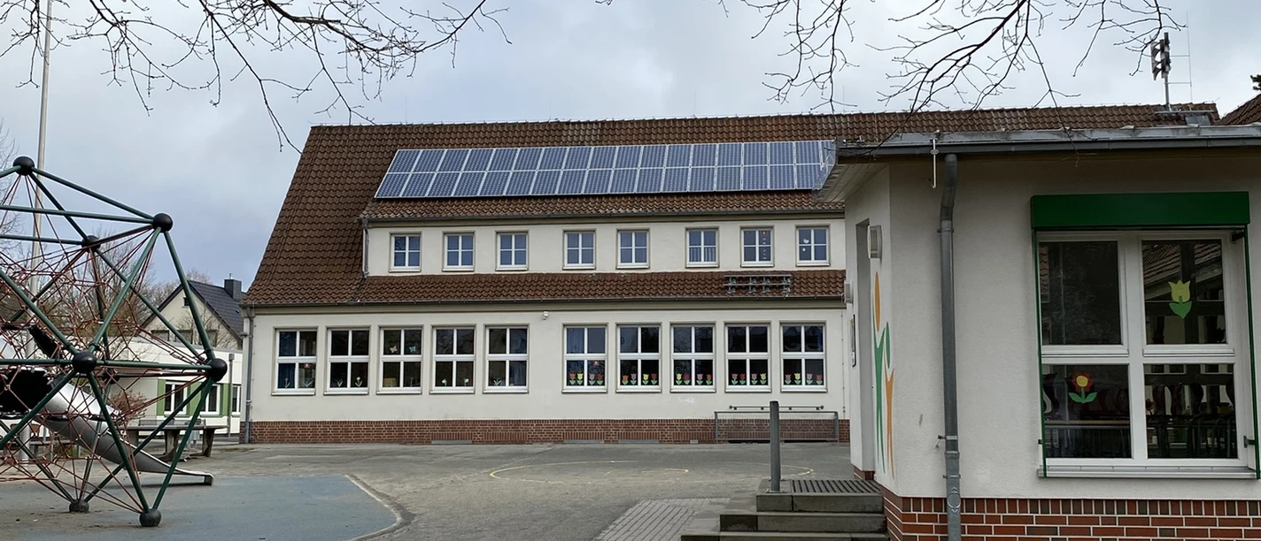Grudnschule Ehmen Mörse.JPEG Außenansicht der Grundschule Ehmen-Mörse mit Schulhof, Sandkasten und einem Klettergerüst.