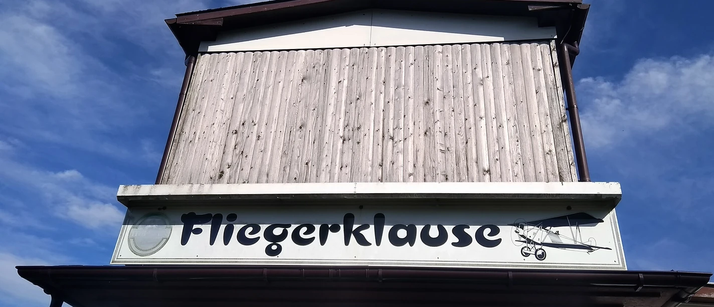 Fassade mit Fliegerklause-Schriftzug und Flugzeug