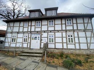 Fassade eines zweistöckigen Fachwerkhauses mit weißen Wänden und einem barrierefreien Eingang.