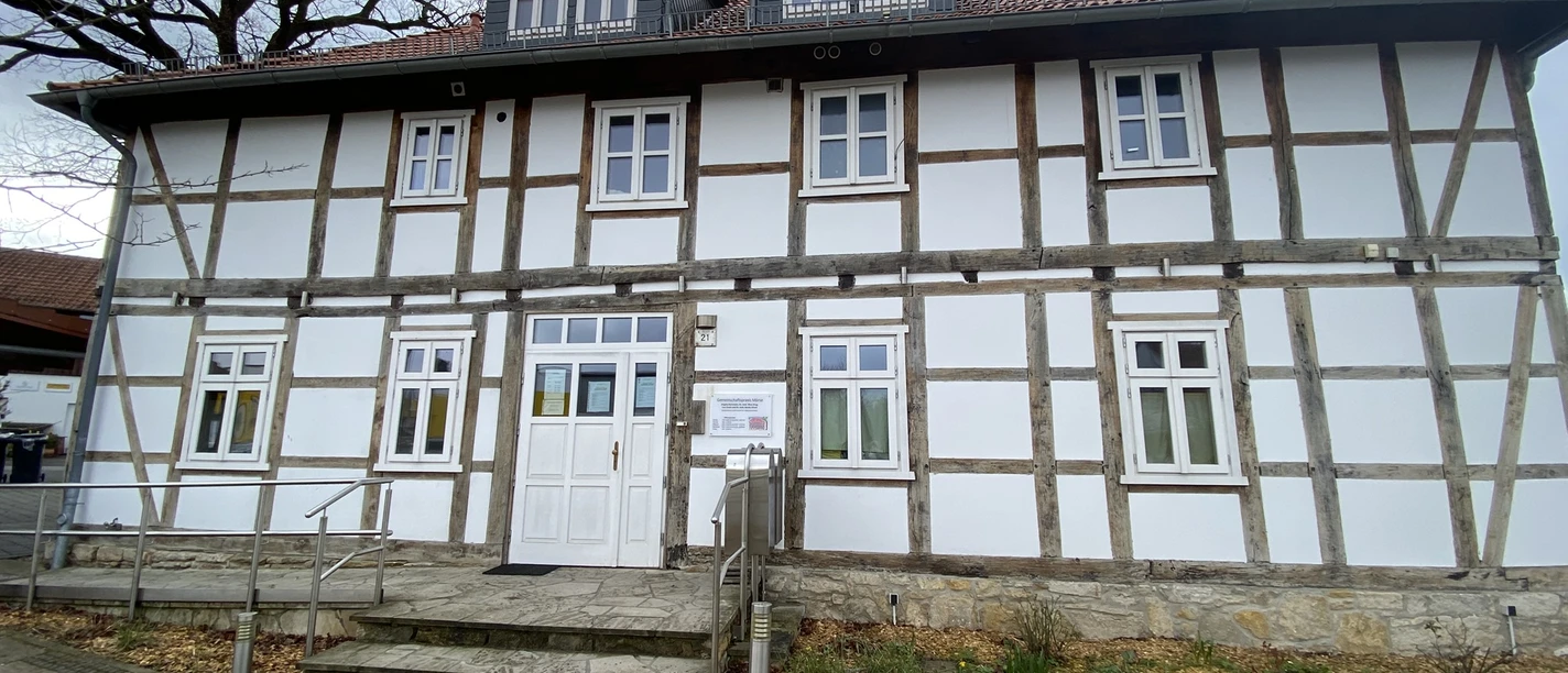 Gemeinschaftspraxis Mörse 2.JPEG Fassade eines zweistöckigen Fachwerkhauses mit weißen Wänden und einem barrierefreien Eingang.