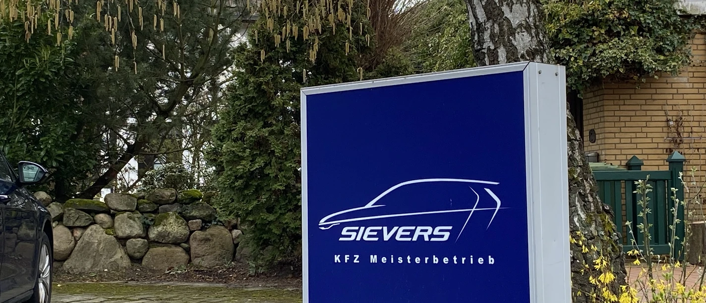 Sievers KFZ Meisterbetrieb.JPEG Firmenschild der Autowerkstatt Sievers in einem begrünten Einfahrtsbereich.