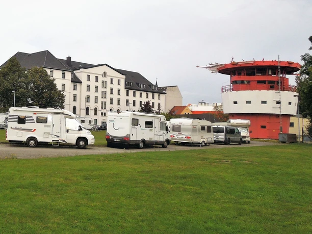 havencamp Bremerhaven 1 (c) Havenhostel_WEB.jpg Kopf des Leuchtturms Großer Vogelsand mit Wohnmobilden davor auf dem Gelände des Havencamps Bremerhaven