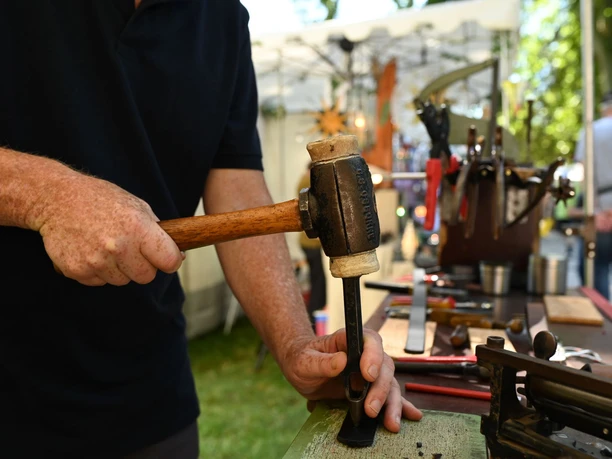 Kunsthandwerkermarkt Hanau Handwerker bearbeitet Metall mit Hammer