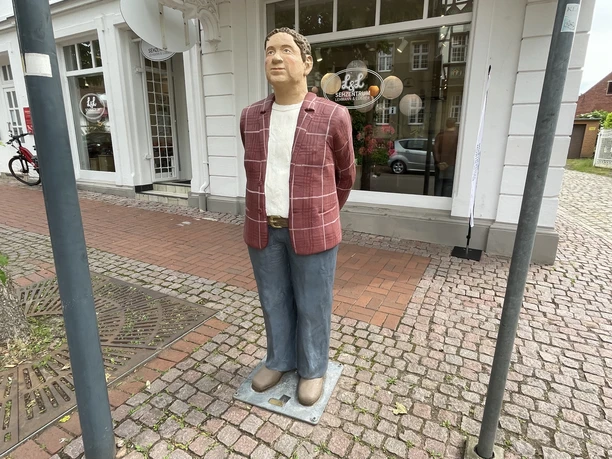 Herr Meyer Die lebensgroße Figur 'Herr Meyer' mit rot-karierter Jacke steht auf einem Gehweg in Petershagen.