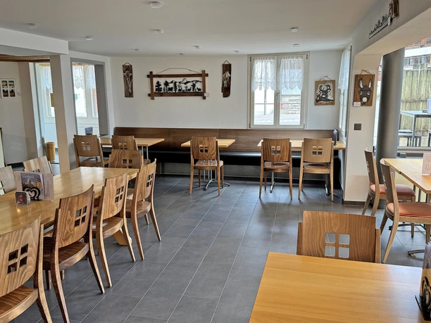 Salle de restaurant Rössli Salle à manger lumineuse du restaurant Rössli, avec des tables et des chaises ainsi que divers objets accrochés aux murs, qui sont à vendre
