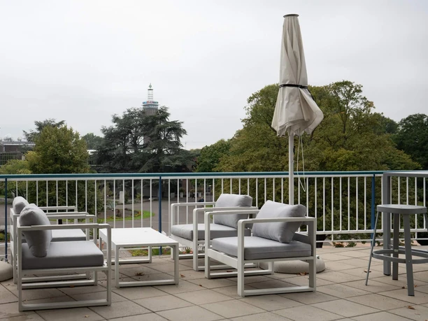 PARK Café Cologne The terrace of the PARK Café, featuring white lounge chairs, umbrellas, and a view of the greenery