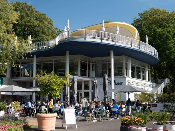 PARK Café Köln Terrasse des PARK Café in Köln mit Gästen, Sonnenschirmen und rundem Bau im Grünen