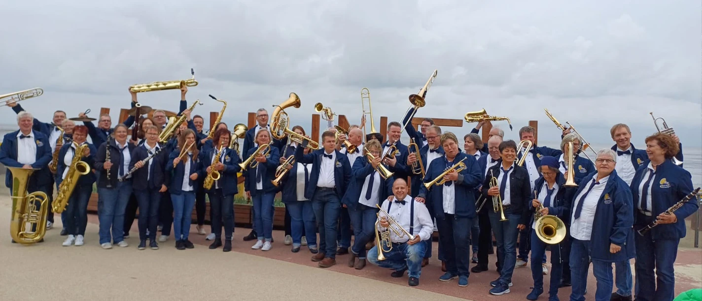 Cuxland-Brass Die Musiker von CuxlandBrass posieren fröhlich mit ihren Blasinstrumenten direkt an der Küste.