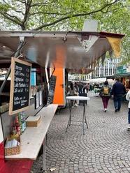 MarktTreff at Rudolfplatz Coffee stand with a price board at the MarktTreff on Rudolfplatz under green trees