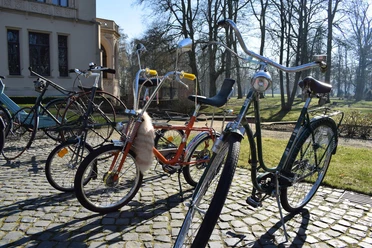 3596_1005_1_g.jpg Verschiedene ausgefallene Fahrräder stehen auf dem Kopfsteinpflaster vor dem Schloss Evenburg.