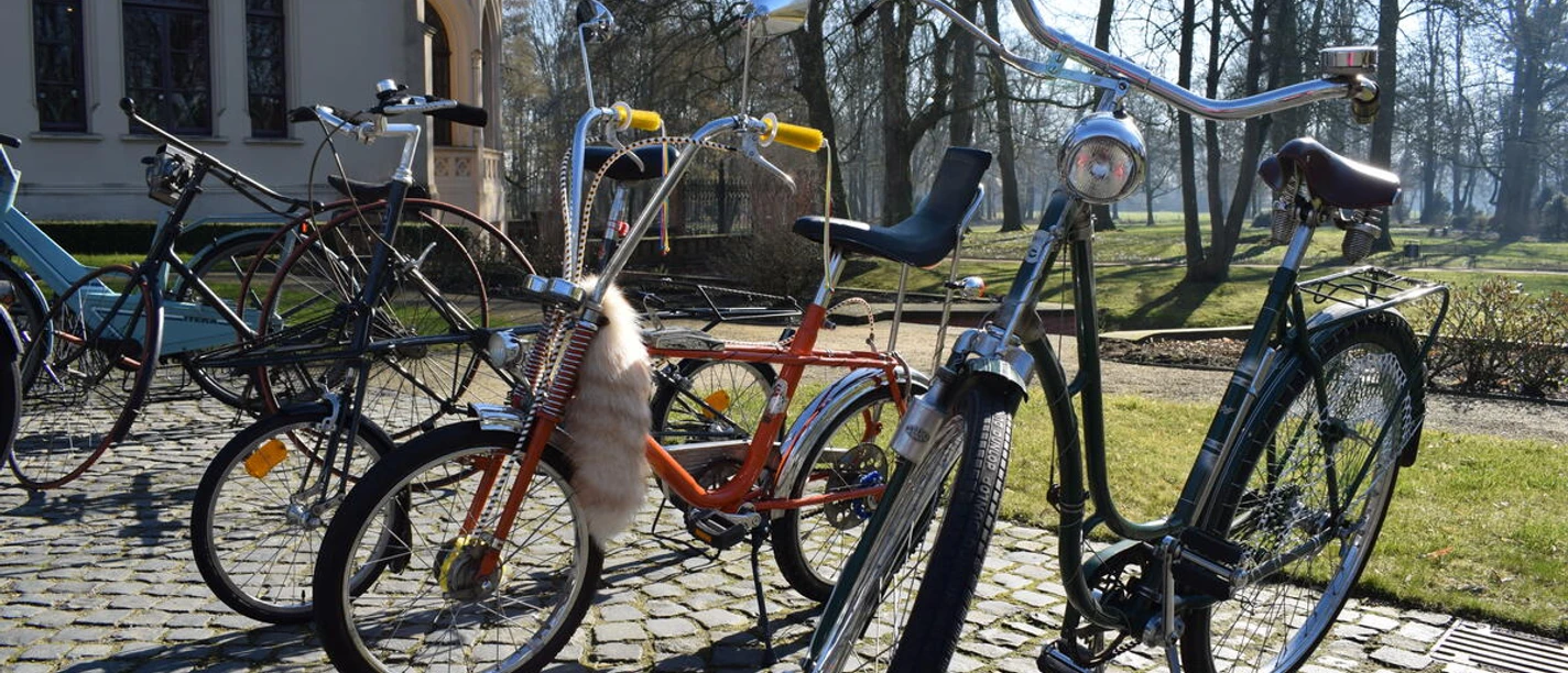 3596_1005_1_g.jpg Verschiedene ausgefallene Fahrräder stehen auf dem Kopfsteinpflaster vor dem Schloss Evenburg.