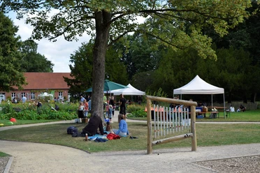 3596_1283_1_g.jpg Besucher des Familienpicknicks im Park der Evenburg entspannen auf einer Wiese mit Zelten.