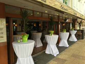Terrasse Auf dem Bild ist die Terrasse des Restaurants zu sehen, ausgestattet mit elegant weiß eingedeckten Stehtischen. Die Atmosphäre ist einladend und perfekt für ein entspanntes Essen im Freien.
