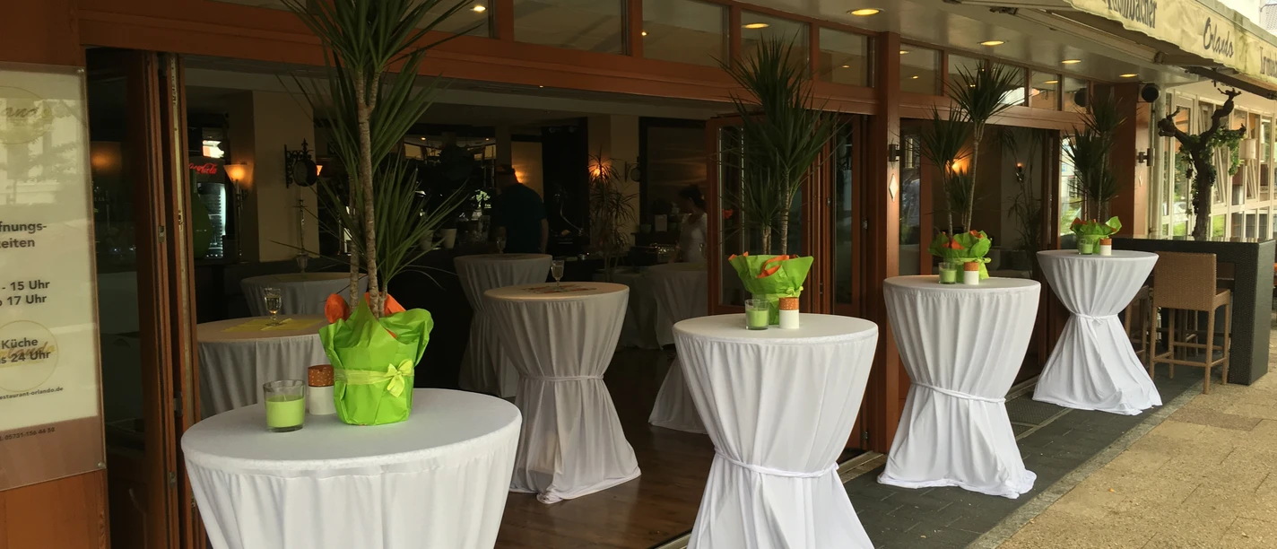 Terrasse Auf dem Bild ist die Terrasse des Restaurants zu sehen, ausgestattet mit elegant weiß eingedeckten Stehtischen. Die Atmosphäre ist einladend und perfekt für ein entspanntes Essen im Freien.