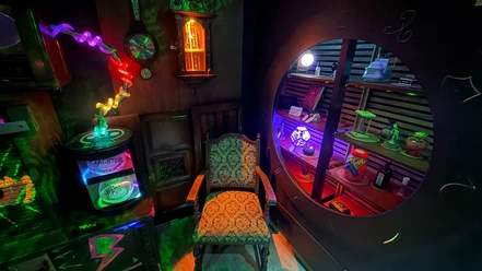 Escape Room MAGIC BOOM Colorful "Magic School" escape room featuring glowing objects, a shelf, and an old chair.