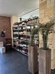 Weinregale in einer Weinhandlung mit Holzkistenwand und großen Glasvasen im Vordergrund