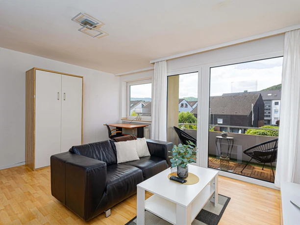 Ferienwohnung Egge Suite - Wohnzimmer Wohnzimmer mit Sofa, Schrank und TV, sowie einen Durchgang zur Terrasse.