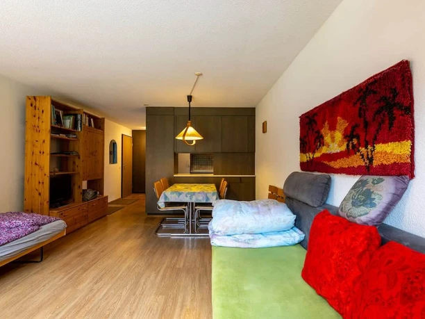 Haus Maya 213: Wohnzimmer Gemütlich eingerichtetes Wohnzimmer mit Sofa und Bett sowie einem grossen Wandbild