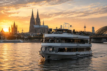 MS Beethoven Party boat on the Rhine in front of Cologne Cathedral and the Hohenzollern Bridge at sunset