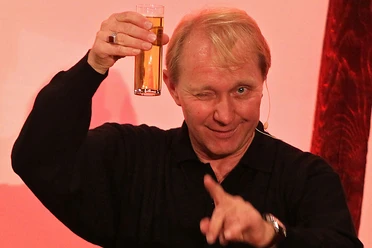 Michael Dirkmann Michael Dirkmann zwinkert, hebt ein Bierglas und zeigt lachend in die Kamera