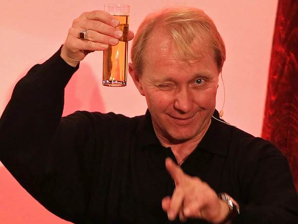Michael Dirkmann Michael Dirkmann zwinkert, hebt ein Bierglas und zeigt lachend in die Kamera