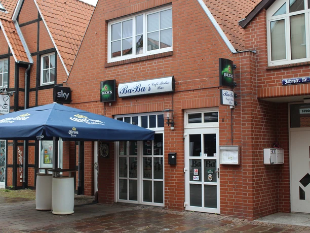 Baba's Bistro in een rood bakstenen gebouw met blauwe parasols en grote ramen.