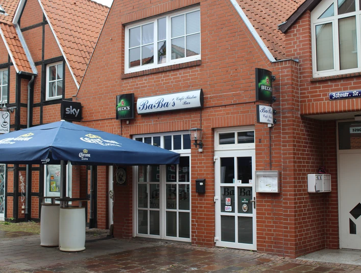 Baba´s Bistro Baba's Bistro in einem roten Backsteingebäude mit blauen Sonnenschirmen und großen Fenstern.