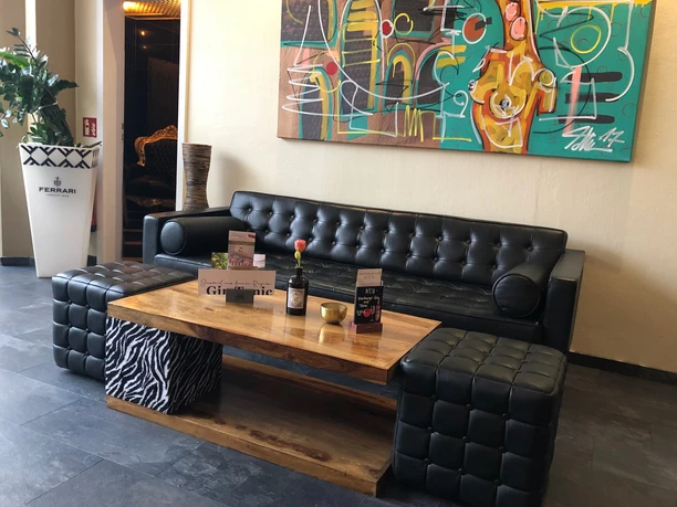 Een stijlvol ingerichte loungeruimte met een zwarte leren bank en salontafel voor kunst aan de muur.