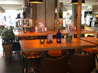 Modern café met houten tafels, leren fauteuils en decoratieve details in warm licht.