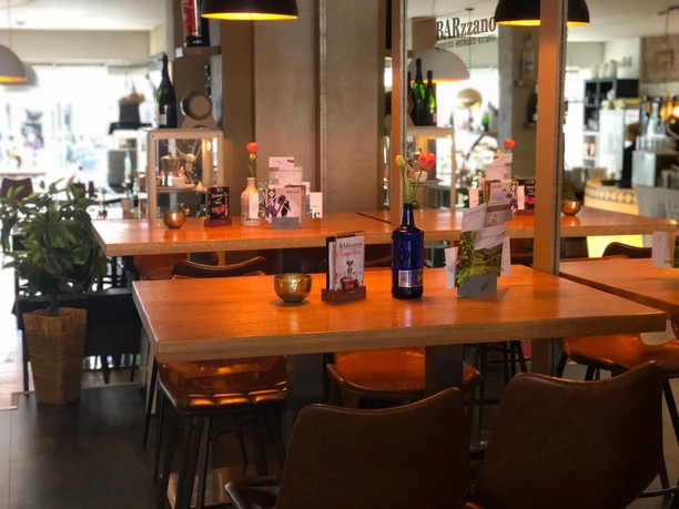 Modern café met houten tafels, leren fauteuils en decoratieve details in warm licht.