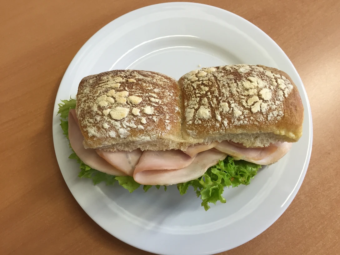 belegtes Brötchen Frisches Brötchen mit Salatblatt und saftigem Schinken auf einem weißen Teller angerichtet.Fresh bread roll with lettuce leaf and juicy ham served on a white plate.Frisk bolle med salatblad og saftig skinke serveret på en hvid tallerken.Vers broodje met sla en sappige ham geserveerd op een wit bord.
