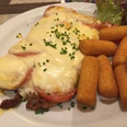 Ein im Ofen gebackenes Schnitzel mit Tomaten, geschmolzenem Käse und Kroketten auf einem Teller.